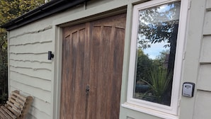 A wooden door with a window above it, a mailbox, and a wooden bench outside.