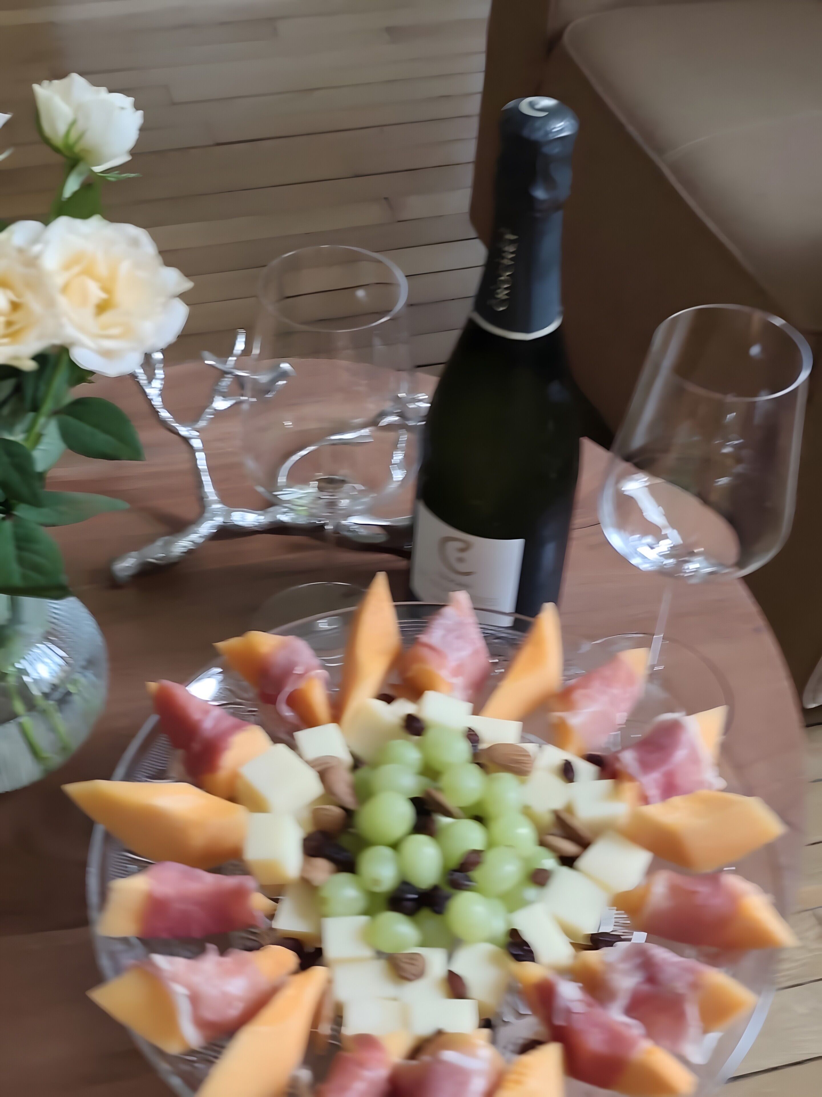 Une table avec un assortiment de fruits et de fromages, une bouteille de vin et deux verres.