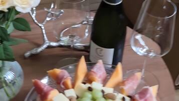 Une table avec un assortiment de fruits et de fromages, une bouteille de vin et deux verres.