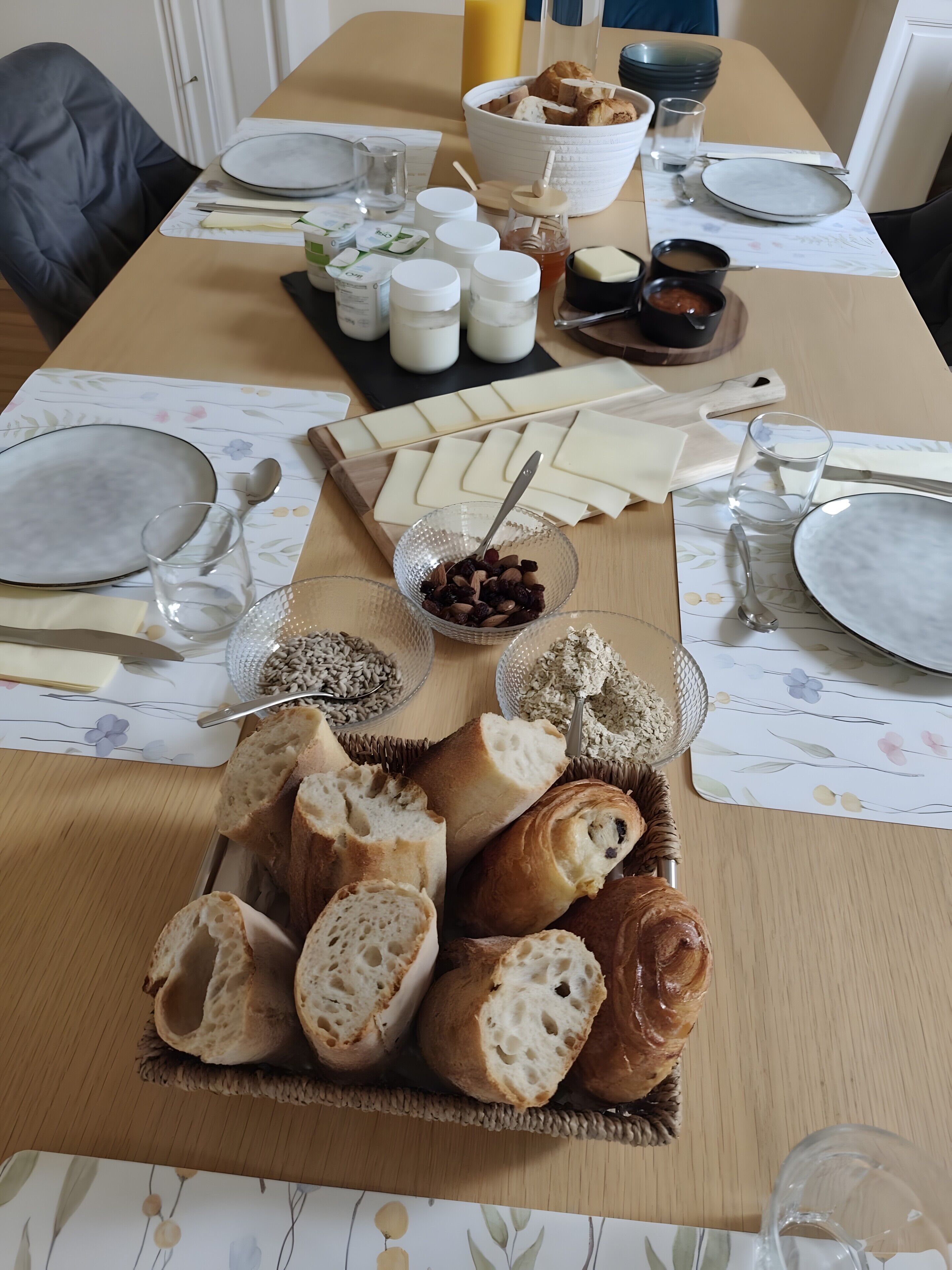 Een gedekte tafel met brood, kaas, noten en toevoegingen.