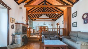 Uma sala de estar ampla com teto de madeira alto, lareira, sofá e mesa de centro.