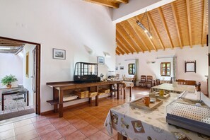 A spacious room with a high wooden ceiling, a dining area with a table and chairs, and a kitchen area with a counter and appliances. - Casa de Campo Vale do Asno-Bungalow '6' with Shared Pool, Wi-Fi and Air Conditioning (Castro Marim)