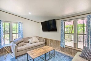 Una habitación con sofá, mesa de centro y televisor montado en la pared.