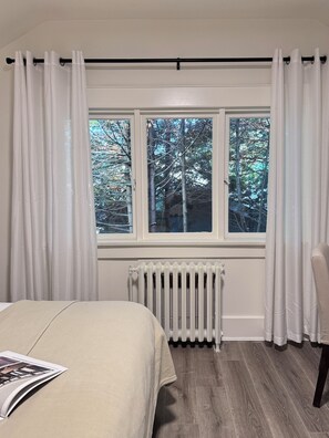 Une chambre à coucher avec un lit, un radiateur et une fenêtre avec des rideaux.