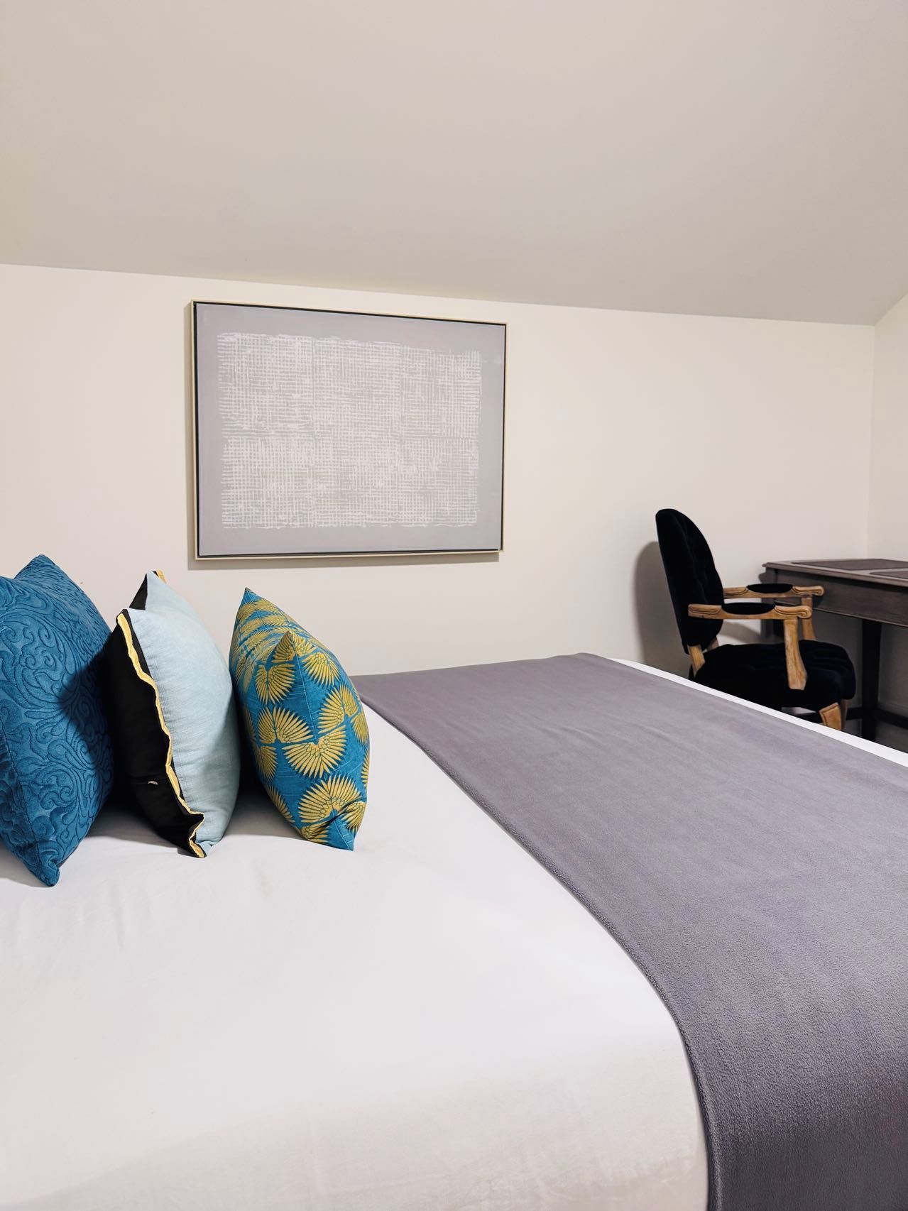 A hotel room with a bed, a desk, and a chair.