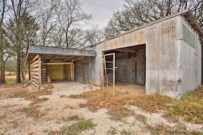 A dilapidated barn with a partially open door and a ladder leaning against it.
