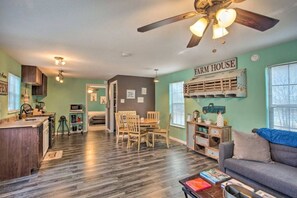 A cozy interior with a dining area, a sofa, a ceiling fan, and a kitchen.