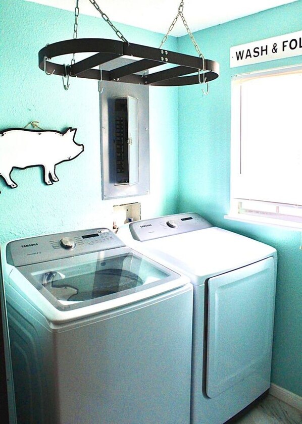 A laundry area with two washing machines, a drying rack, and a wall-mounted heater.