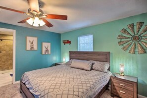 A bedroom with a bed, a nightstand, a wall clock, and a ceiling fan.
