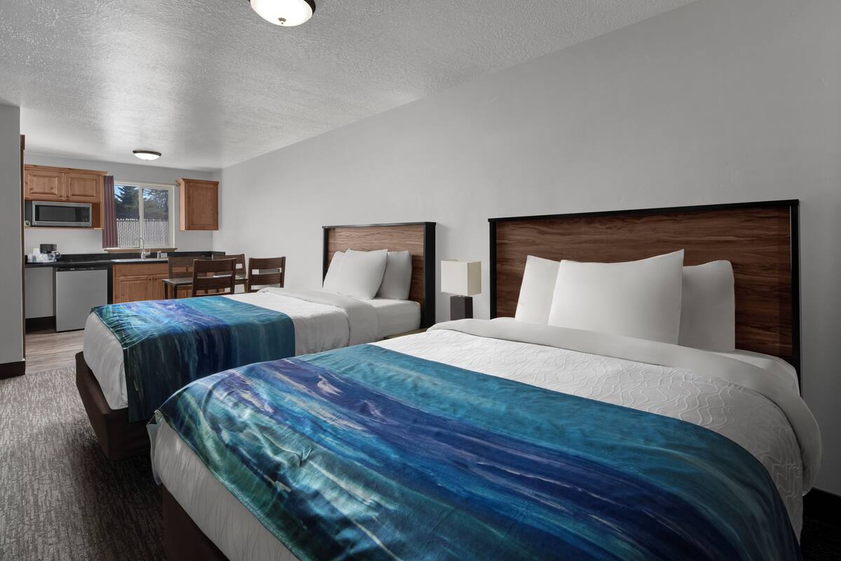 Une chambre d’hôtel avec deux lits, une kitchenette et un coin repas.