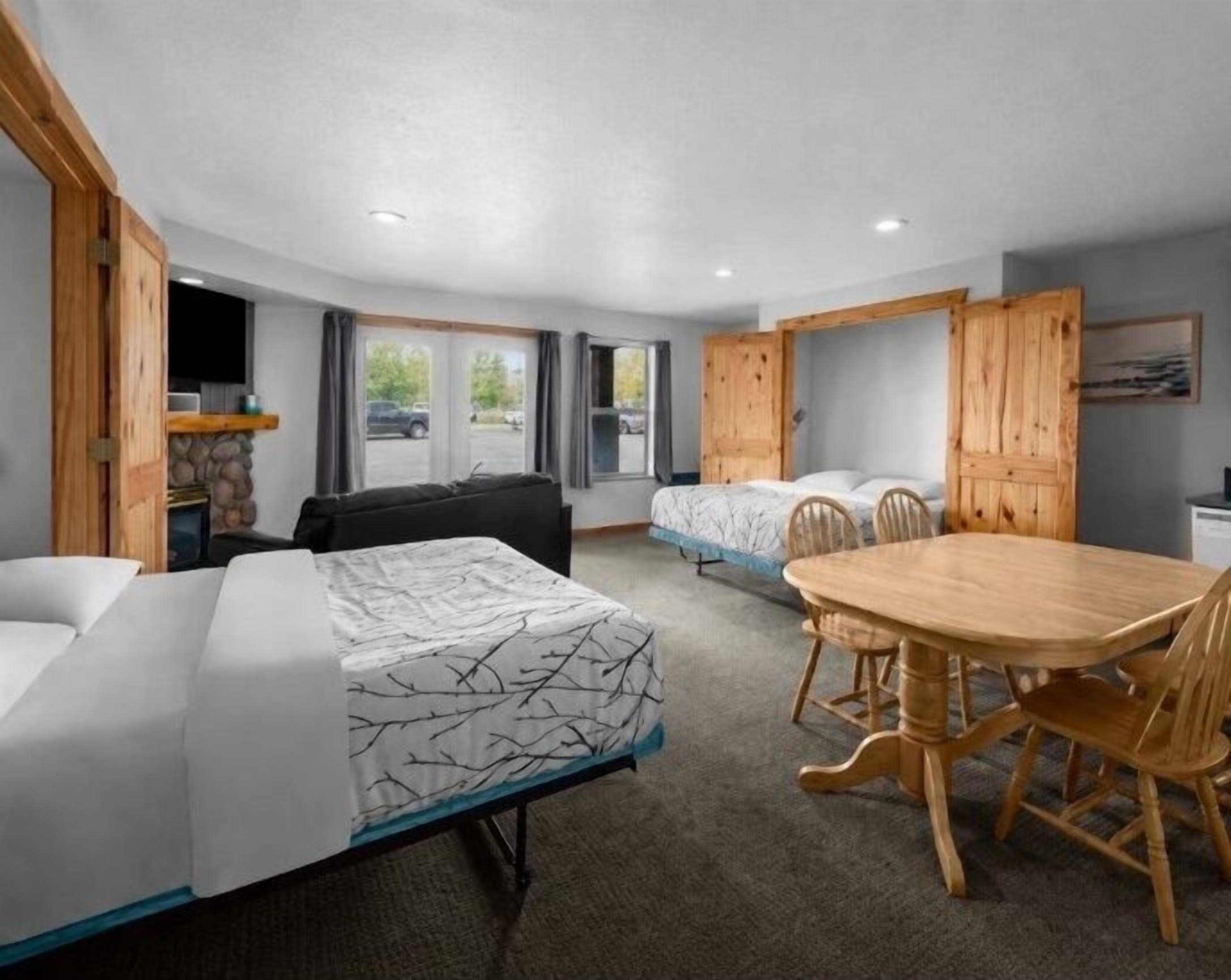 Una habitación de hotel con una cama, un sofá, una mesa de comedor y sillas, y un televisor.