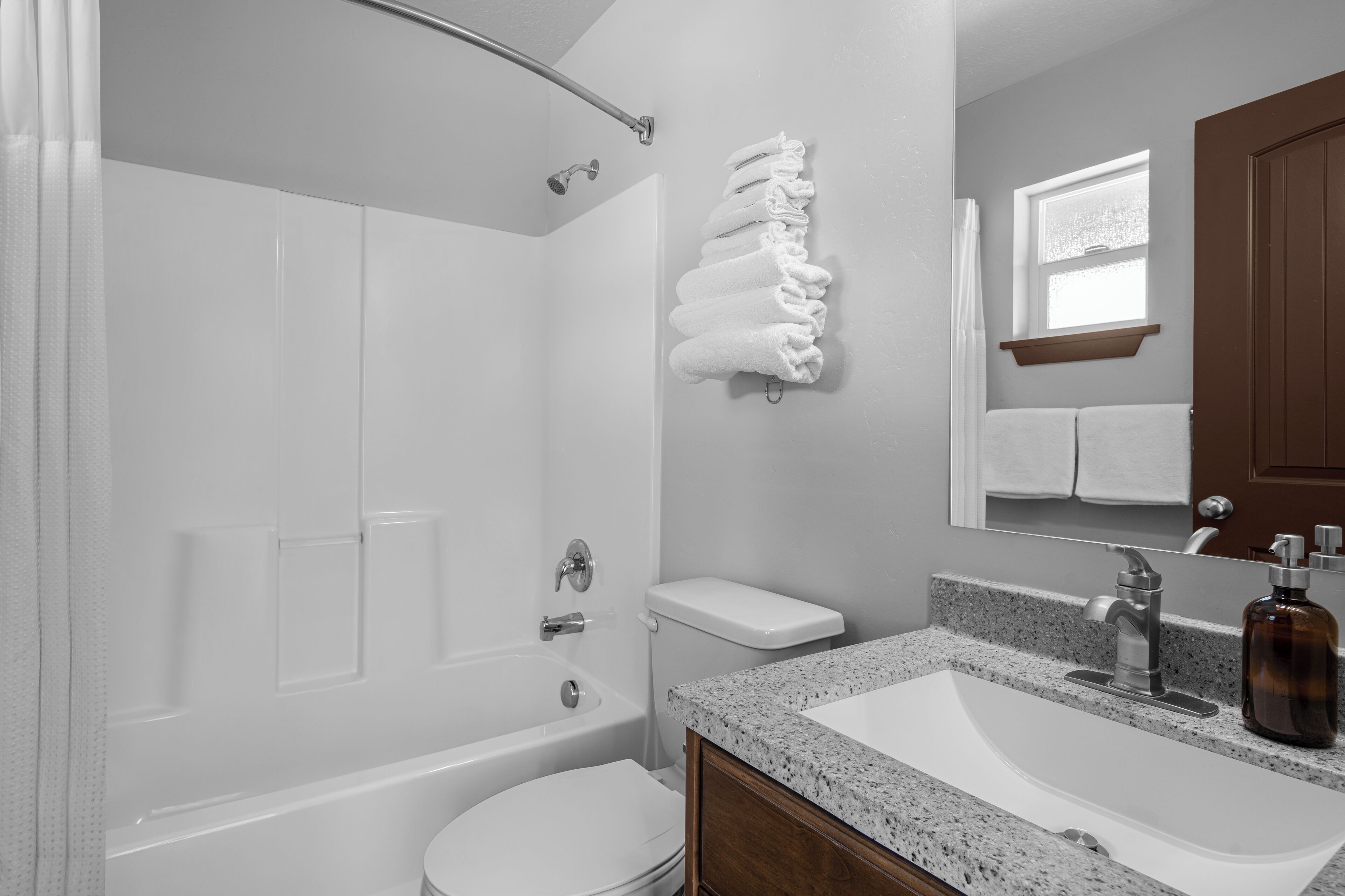 A bathroom with a bathtub, toilet, sink, and a mirror.