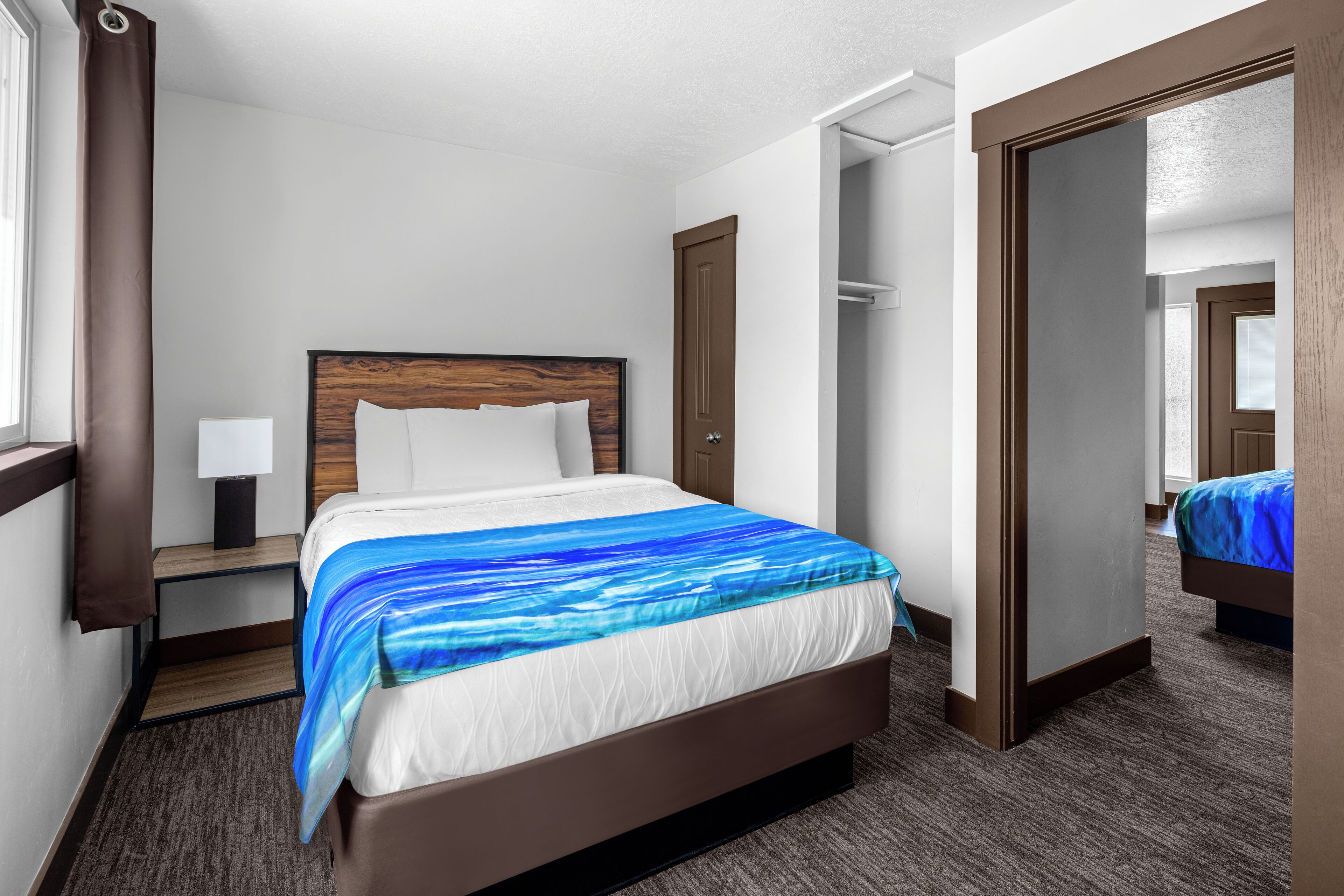 Une chambre d’hôtel avec un grand lit, une table de chevet, une lampe, une armoire et un miroir.