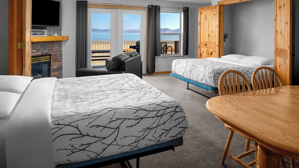 Ett hotellrum med två sängar, ett matbord i trä, en TV och en öppen spis.