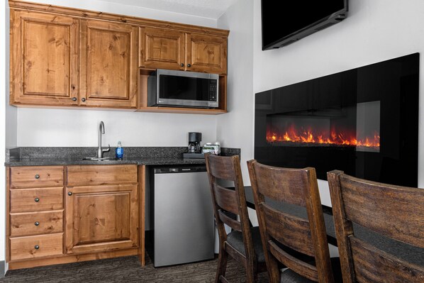 A modern kitchen with wooden cabinets, a built-in microwave, a dishwasher, and a black countertop. - Sun Outdoors Garden City Utah (Garden City)
