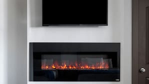 Ett modernt vardagsrum med en platt-TV som är monterad ovanför en öppen spis.