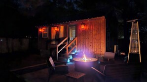 A wooden cabin with a fire pit, outdoor seating, and a staircase leading to the entrance. - Tiny Home Retreat with Bunnies, Chickens & a Goat near Gulf Coast Beach Navarre (Navarre)