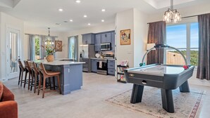 A modern kitchen with a central island, bar stools, a pool table, and a view of the outdoors. - Charming 4-bedroom Retreat Near Baylor Hospital & VA Hospital (Temple)