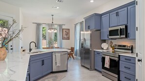 A modern kitchen with blue cabinets, stainless steel appliances, and a marble countertop. - Charming 4-bedroom Retreat Near Baylor Hospital & VA Hospital (Temple)