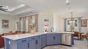 A modern kitchen with a large island, built-in cabinets, and a dining area with a table and chairs. - Charming 4-bedroom Retreat Near Baylor Hospital & VA Hospital (Temple)
