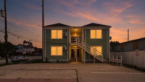 A two-story house with a staircase leading to the entrance, a fenced yard, and a parked car. - Stylish EaDo Apt | Restaurants, Stadiums, Venues (Houston)