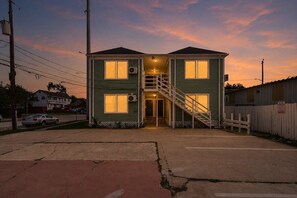 Ein zweigeschossiges Haus mit einer Treppe zum Eingang, einem umzäunten Garten und einem geparkten Auto.