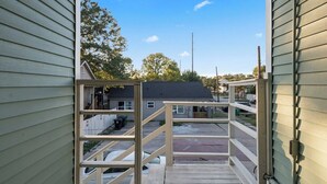 A wooden staircase leading to a gated driveway with a clear view of a residential area and a house in the background. - Stylish EaDo Apt | Restaurants, Stadiums, Venues (Houston)