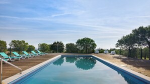 Una piscina con sillones de descanso y un muelle de madera.