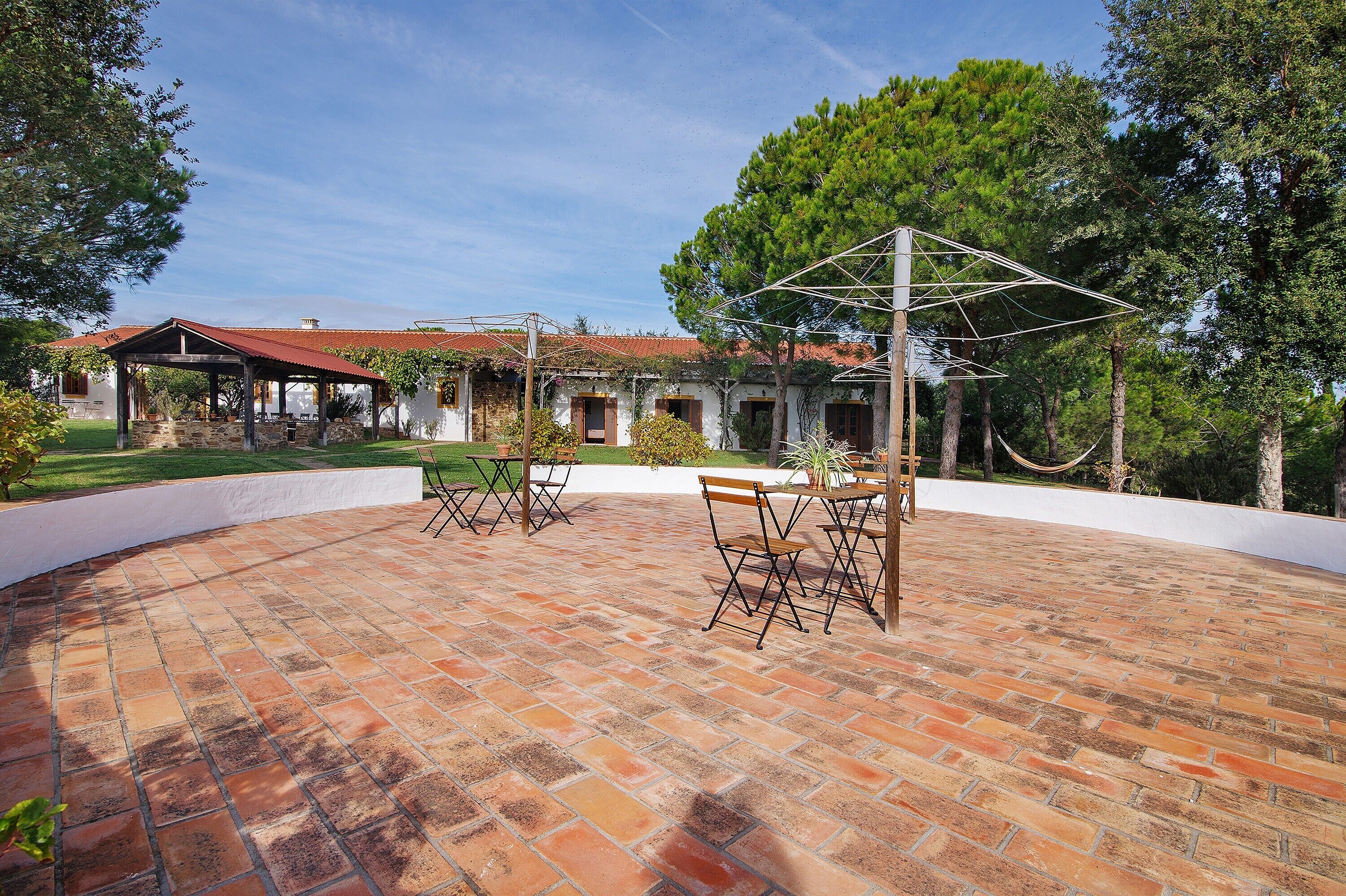 A patio with brick flooring, outdoor furniture, and a covered seating area.