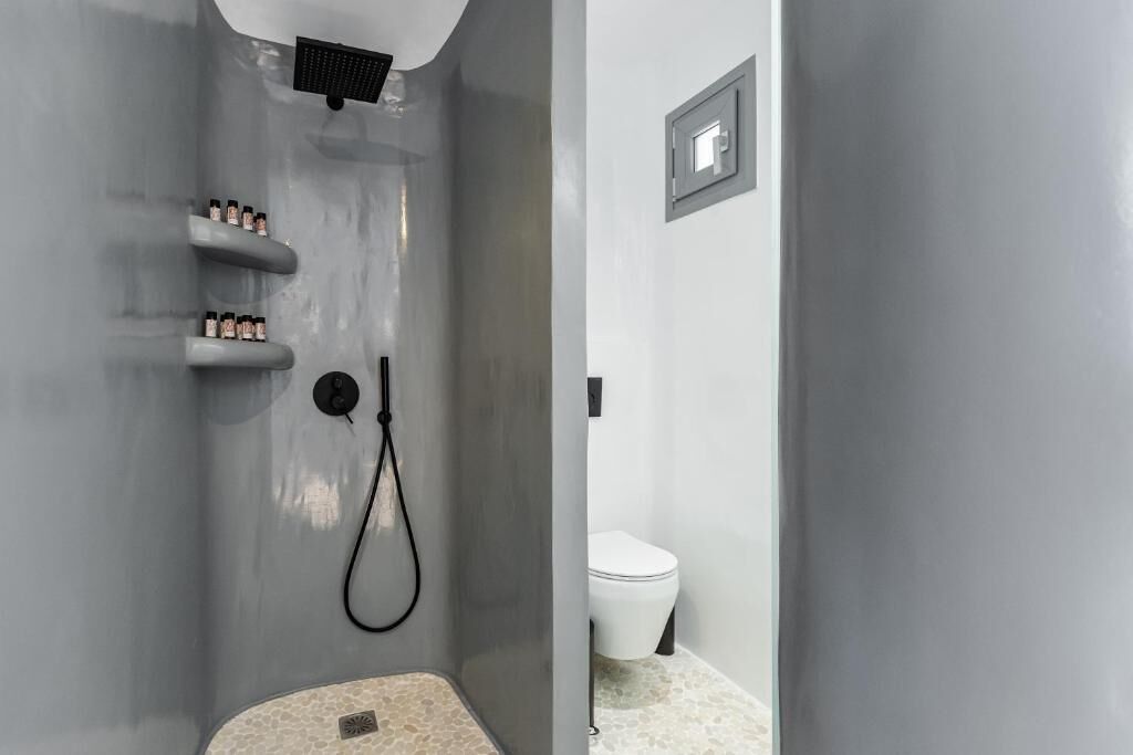 Ein modernes Badezimmer mit Dusche, Toilette und Ablagen für Pflegeprodukte.