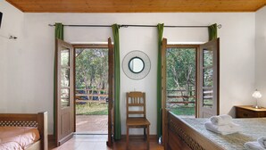A room with a bed, a chair, a mirror, and a view through open doors.