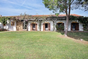 A white building with a tiled roof, wooden shutters, and a grassy yard. - Casa de Campo Vale do Asno-Room 'Quarto 7' with Shared Pool, Wi-Fi and Air Conditioning (Castro Marim)