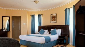 Ein Hotelzimmer mit einem großen Bett, einem Nachttisch, einem Kleiderschrank und einem Spiegel.