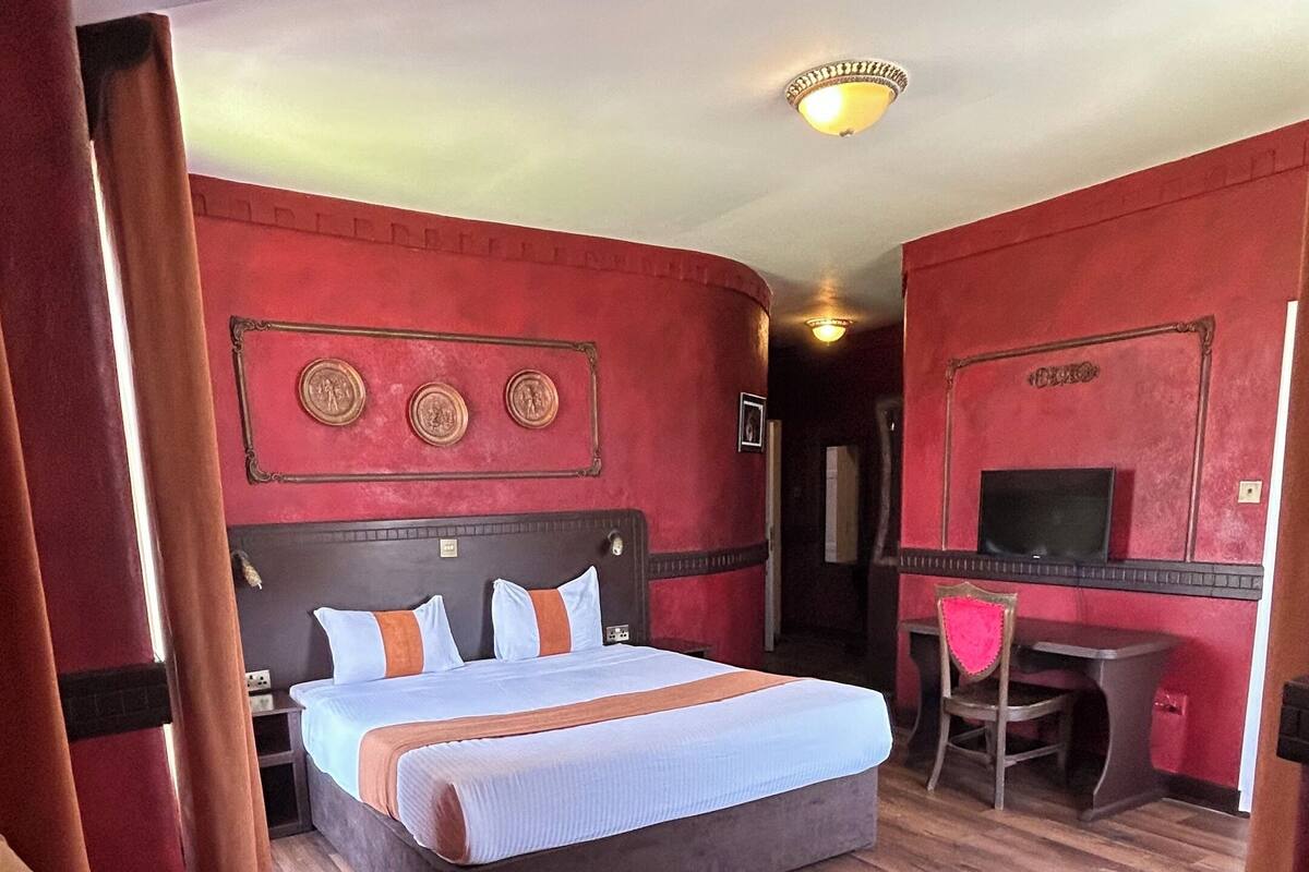 Une chambre d’hôtel avec un grand lit, un bureau et deux chaises.