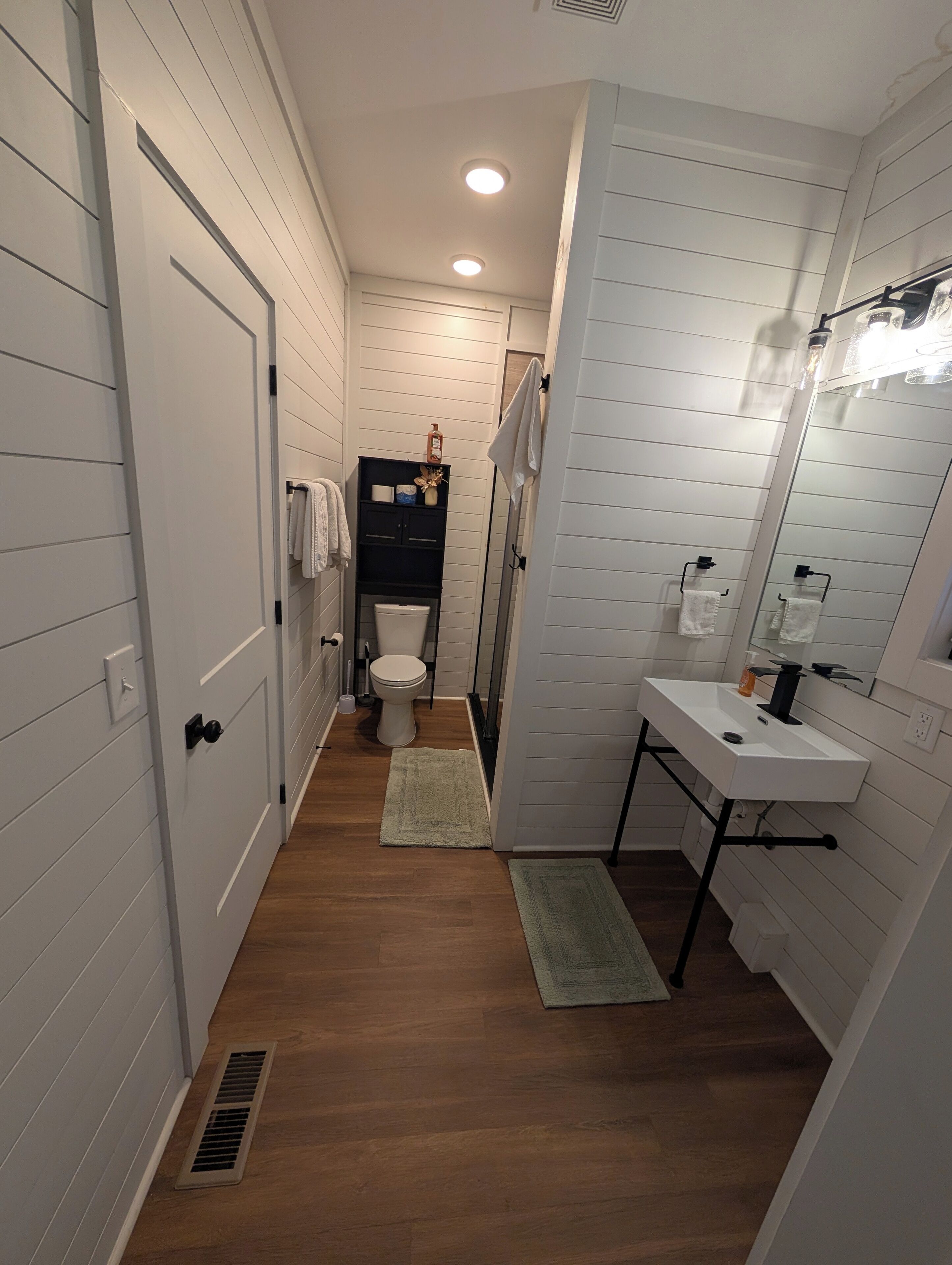 Ein schmales Badezimmer mit Waschbecken, Toilette und Dusche.