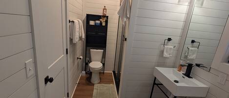 Ein schmales Badezimmer mit Waschbecken, Toilette und Dusche.