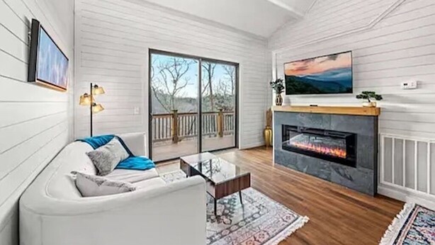 A modern living room with a fireplace, white walls, and a large window.