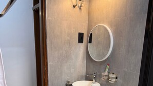 A modern bathroom with a toilet, sink, and mirror. - Jacob's Courts Apartment 6 In Kampala (Kampala)