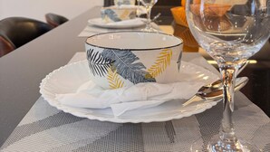 A dining table set with a clear glass wine glass, a decorative bowl, and a plate on a textured placemat. - Jacob's Courts Apartment 6 In Kampala (Kampala)