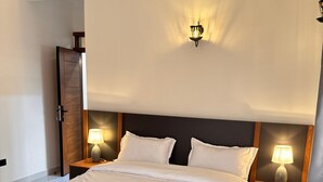 A neatly made bed with white linens, two bedside tables with lamps, and a wooden headboard. - Jacob's Courts Apartment 6 In Kampala (Kampala)