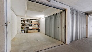 Eine geschlossene Metallrolltür, ein Betonboden und ein Lagerraum mit Regalen und Kisten.
