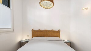 Ein Bett mit einem gewobenen Kopfteil, einer Nachttischlampe und einer Wandleuchte.