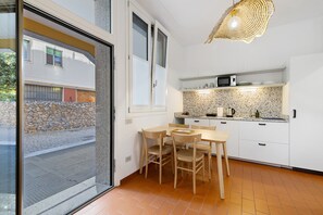 A compact kitchen with white cabinets, a microwave, and a stone wall.
