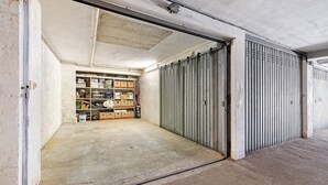 Een gesloten metalen deur, een betonnen vloer en een opslagruimte met planken en dozen.