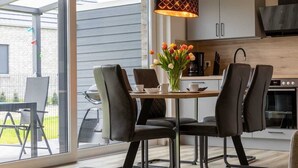 Una cocina moderna con comedor, que cuenta con un amplio ventanal, una mesa de comedor con sillas y un jarrón con flores.