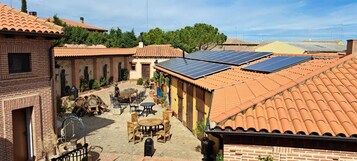 Un patio con un edificio de ladrillo, una mesa con sillas y paneles solares en el techo.