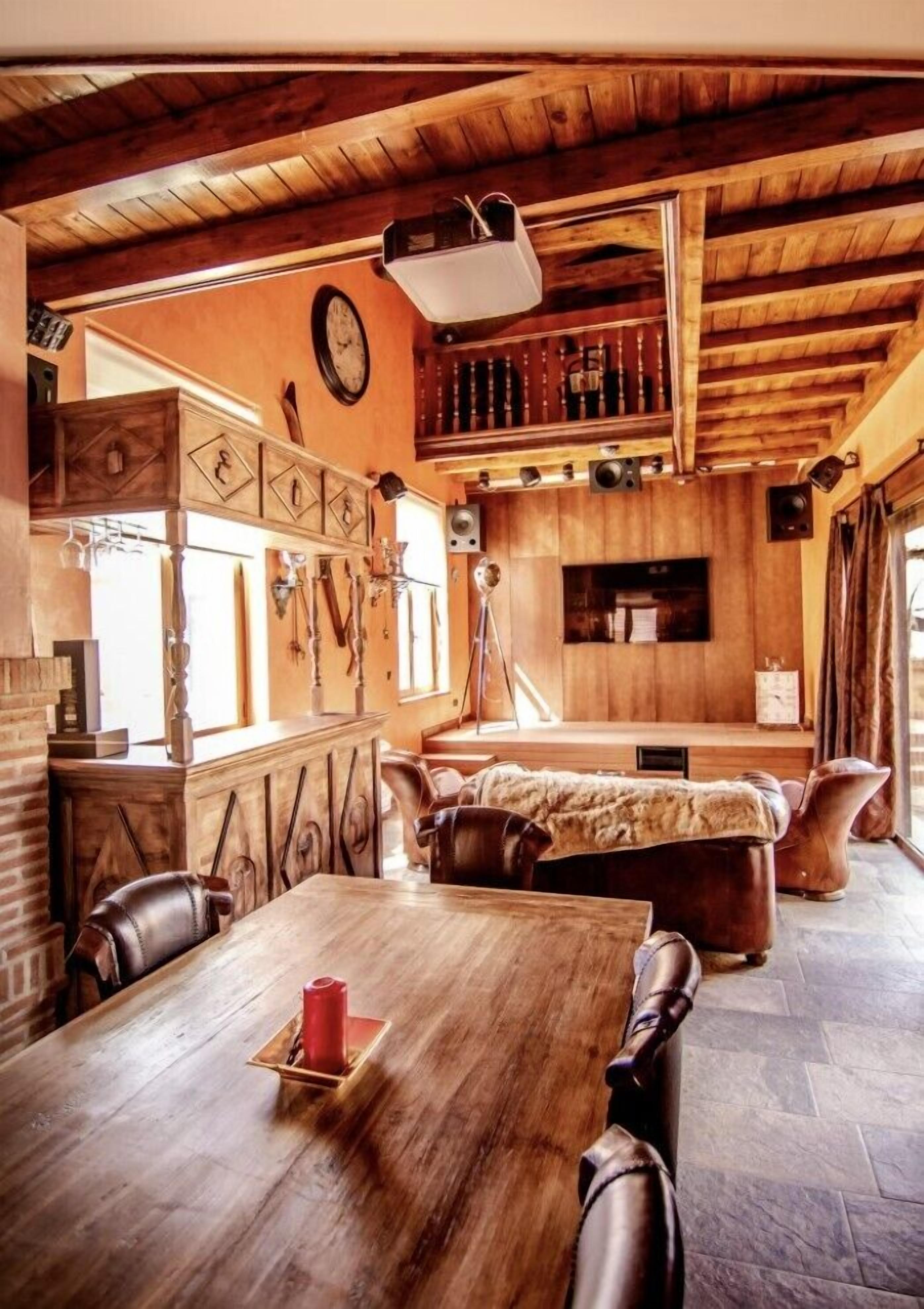 Un interior rústico con una mesa de comedor de madera, sillas de cuero, una chimenea y un ventanal grande.