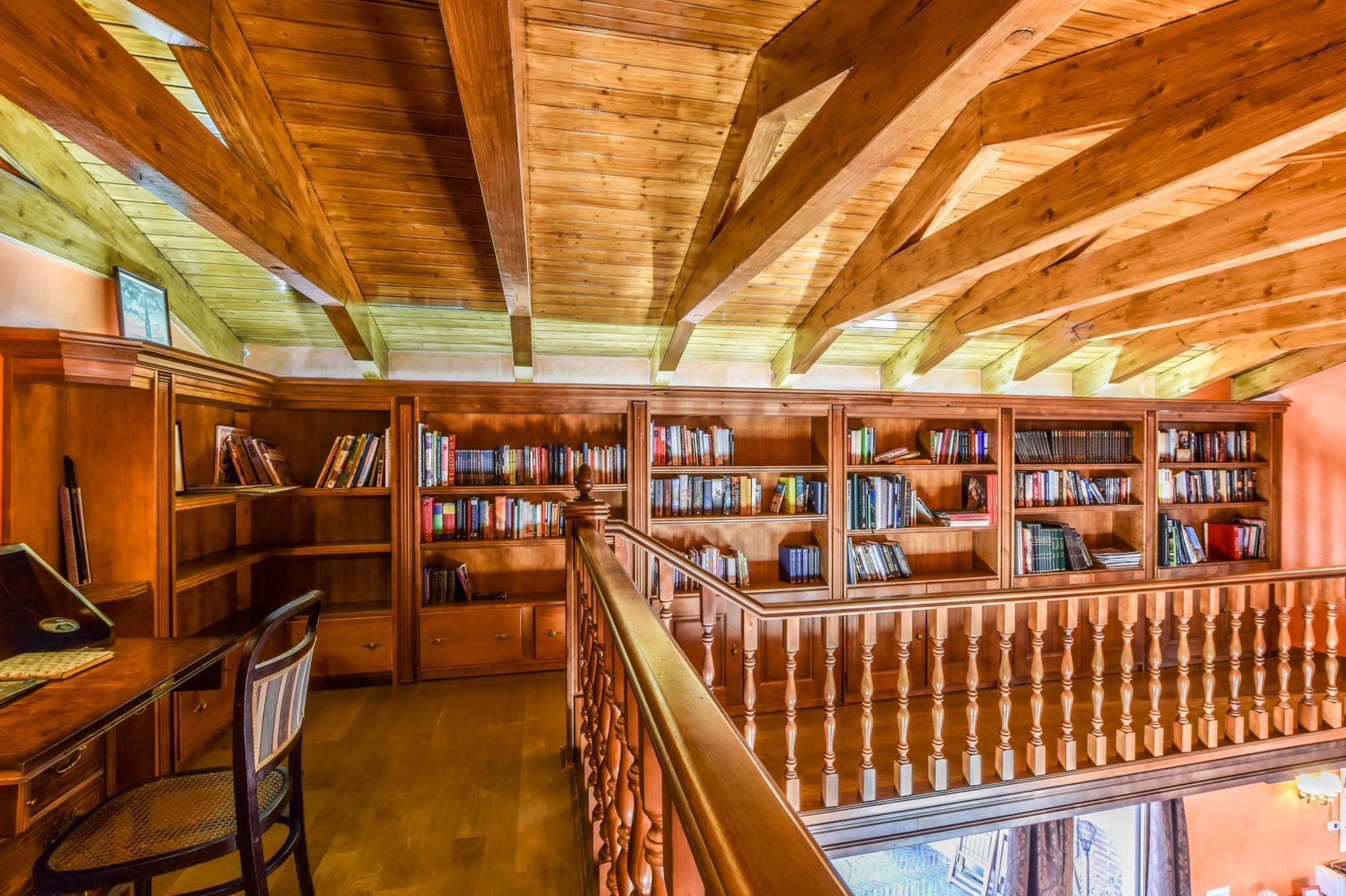 A library with wooden bookshelves and a wooden staircase.