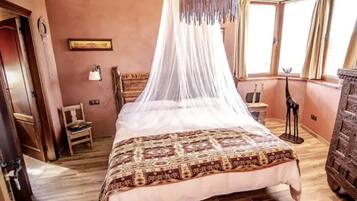 A bedroom with a four-poster bed, a canopy, a wooden dresser, and a chair.