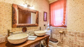 A bathroom with a wooden vanity, two sinks, a large mirror, and a toilet.